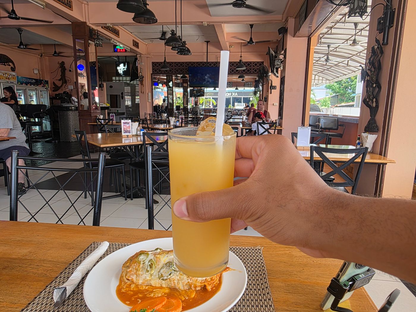 Fresh pineapple juice in hand over a burrito lunch at an open-air Pattaya restaurant, photographed by Danny Flight.